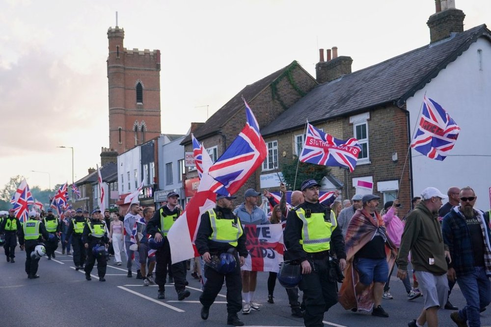 FILE - Police officers escort protesters near the Bell Hotel in Epping, London, Sunday, Aug. 31, 2025 after a temporary injunction that would have blocked asylum seekers from being housed at the hotel was overturned. (AP Photo/Alberto Pezzali, File)