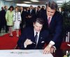 U.S. President Ronald Reagan signs in as Prime Minister Brian Mulroney looks on at the official opening ceremony at the Economic Summit in Toronto in this June 19, 1988 file photo. Mila Mulroney and Nancy Reagan are pictured in the background. (CP PICTURE ARCHIVE - Blaise Edwards)