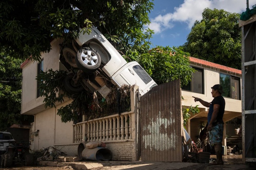 A pickup truck hangs over a fence in Poza Rica, Veracruz state, Mexico, Sunday, Oct. 12, 2025, after rain and flooding. (AP Photo/Felix Marquez)