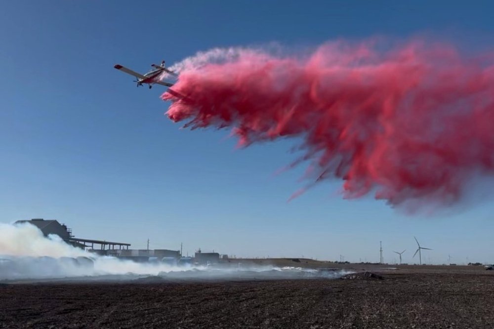 This image provided by Texas A&M Forest Service shows an aircraft contracted by Texas A&M Forest Service dropping fire retardant on the Mill Fire (Texas A&M Forest Service via AP)