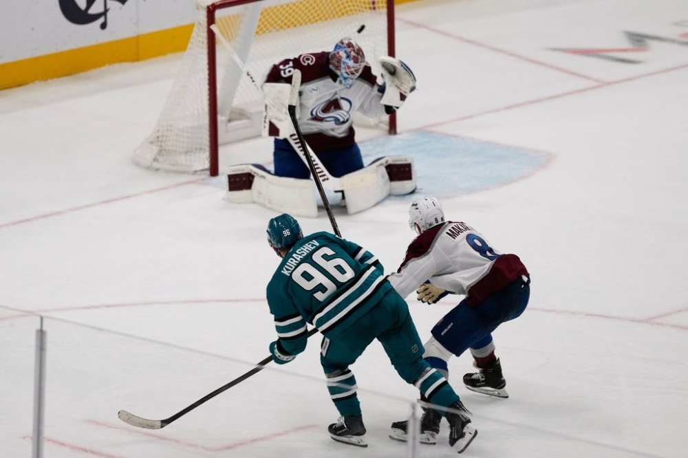 San Jose Sharks center Philipp Kurashev (96) watches his shot score past Colorado Avalanche goaltender Mackenzie Blackwood (39) and defenseman Cale Makar (8) during overtime of an NHL hockey game in San Jose, Calif., Saturday, Nov. 1, 2025. (AP Photo/Jeff Chiu)