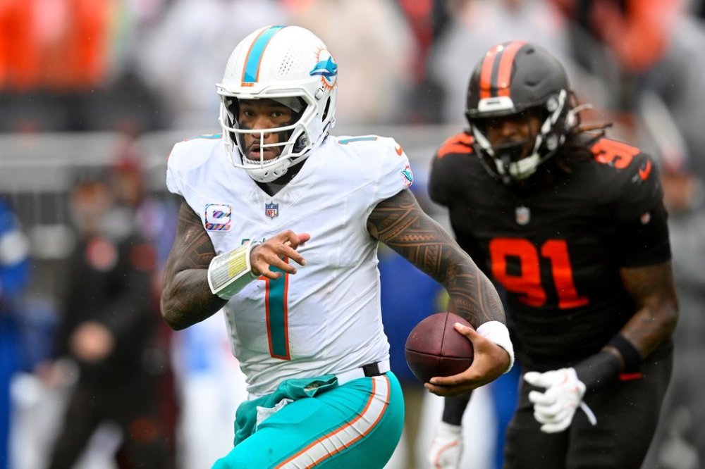 Miami Dolphins quarterback Tua Tagovailoa (1) scrambles from Cleveland Browns defensive end Alex Wright (91) in the first half of an NFL football game in Cleveland, Sunday, Oct. 19, 2025. (AP Photo/David Richard)