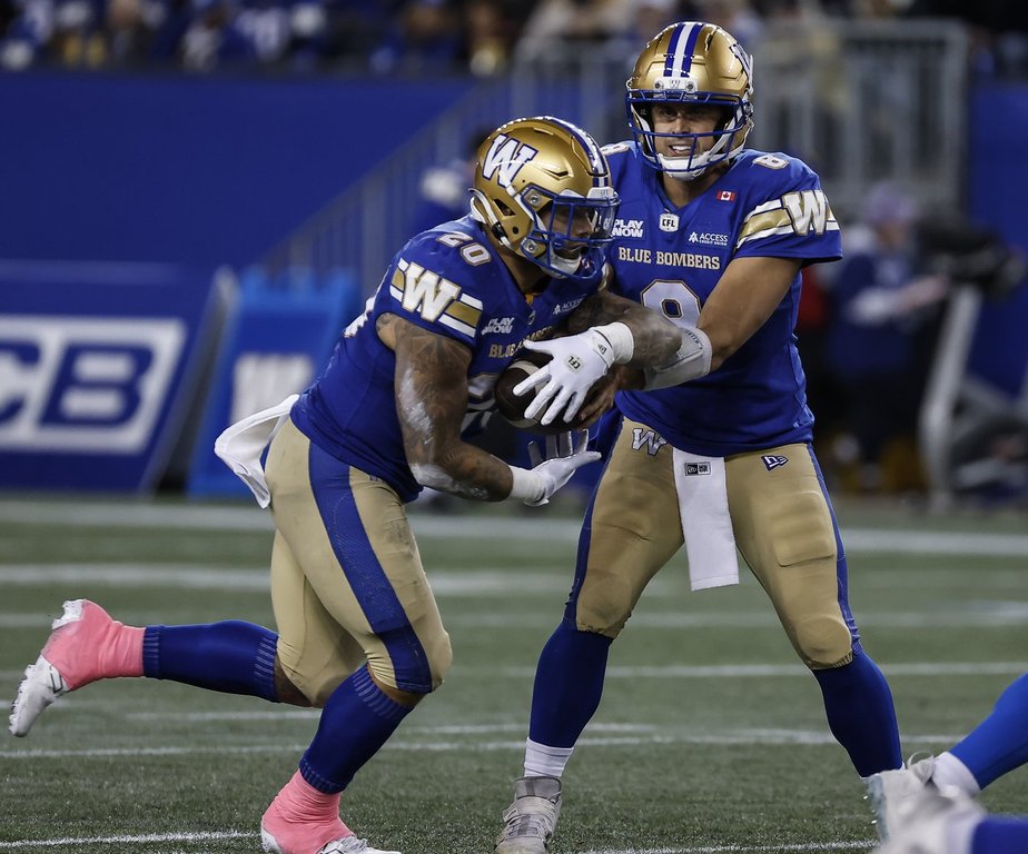 Winnipeg Blue Bombers quarterback Zach Collaros (8) hands off to Brady Oliveira (20) during first half CFL action against the  Saskatchewan Roughriders in Winnipeg, Friday, Oct. 17, 2025. THE CANADIAN PRESS/John Woods