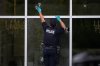 An RCMP officer places evidence markers beside bullet holes in the windows of a café in Surrey, B.C. on Thursday, Aug. 7, 2025. THE CANADIAN PRESS/Darryl Dyck