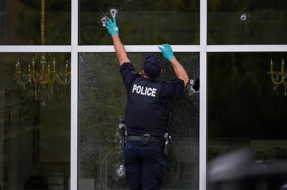 An RCMP officer places evidence markers beside bullet holes in the windows of a café in Surrey, B.C. on Thursday, Aug. 7, 2025. THE CANADIAN PRESS/Darryl Dyck
