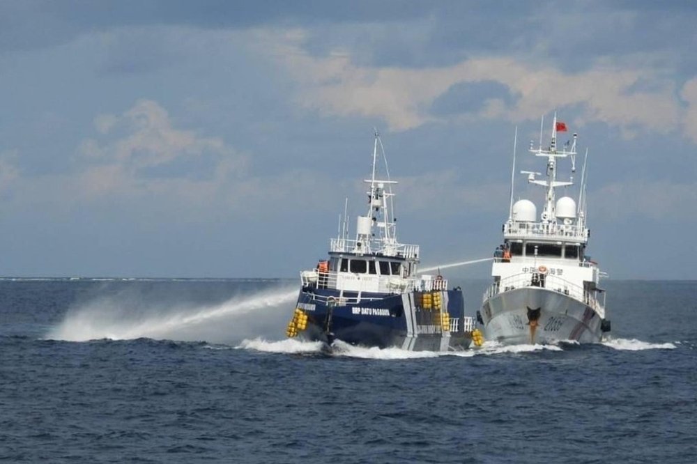 In this photo provided by the Philippine Coast Guard, a Chinese Coast Guard vessel, right, fires it's water cannon at the Philippine's BRP Datu Pagbuaya near Philippine occupied Thitu island locally called Pag-asa island at the South China Sea on Sunday Oct. 12, 2025. (Philippine Coast Guard via AP)