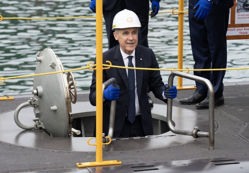 Prime Minister Mark Carney smiles as he climbs down a ladder into a submarine during a tour of the Hanwha Ocean Shipyard in Geoje Island, South Korea, Thursday Oct. 30, 2025. THE CANADIAN PRESS/Adrian Wyld