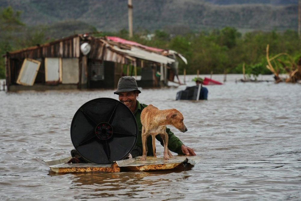 A man wades through floodwaters with his dog and belongings from his home flooded by Hurricane Melissa in Santiago de Cuba, Wednesday, Oct. 29, 2025. (AP Photo/Ramón Espinosa)