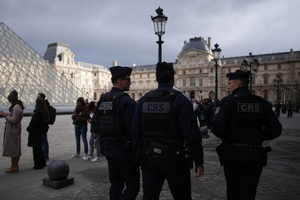Riot police officers patrol as people queue to enter Le Louvre museum Monday, Oct. 27, 2025 in Paris. (AP Photo/Christophe Ena)