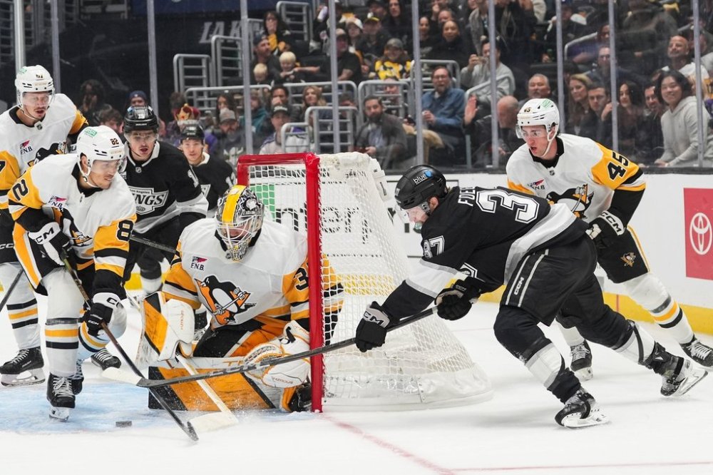 Los Angeles Kings left wing Warren Foegele (37) attempts a shot under defense by Pittsburgh Penguins defenseman Parker Wotherspoon (28) during the second period of an NHL hockey game Thursday, Oct. 16, 2025, in Los Angeles. (AP Photo/Jae C. Hong)