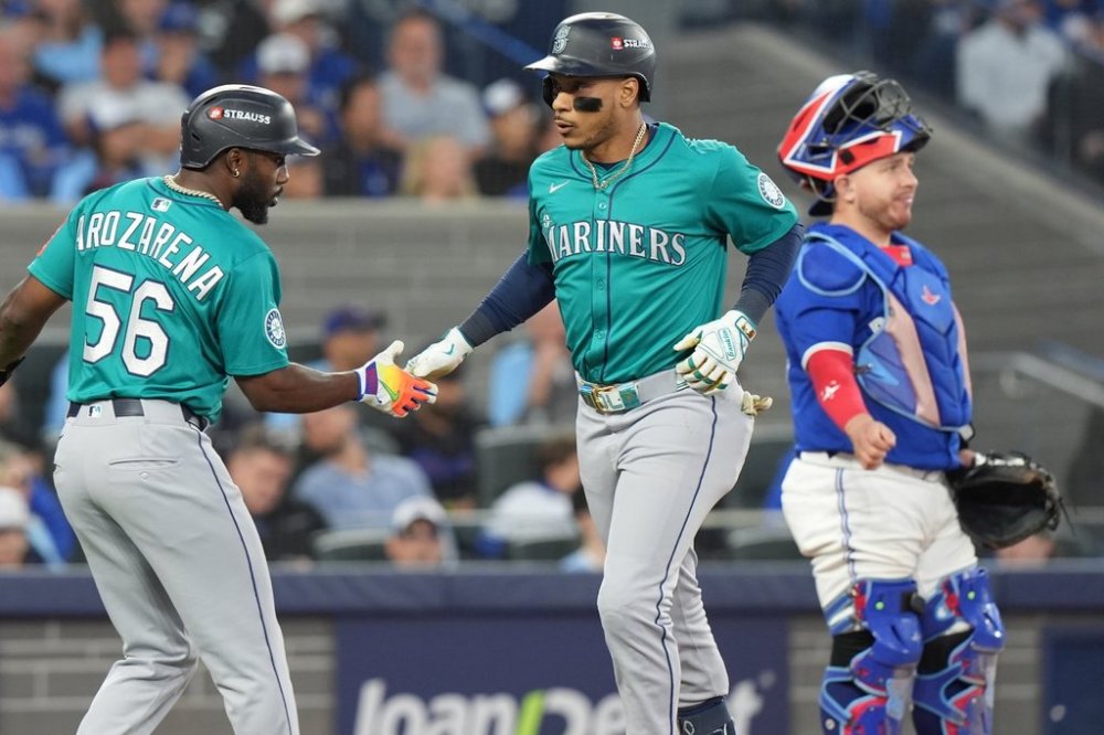 Seattle Mariners second baseman Jorge Polanco celebrates his three-run homer with teammate Randy Arozarena as Blue Jays catcher Alejandro Kirk looks on during fifth inning American League Championship Series baseball action in Toronto on Oct. 13, 2025. THE CANADIAN PRESS/Frank Gunn