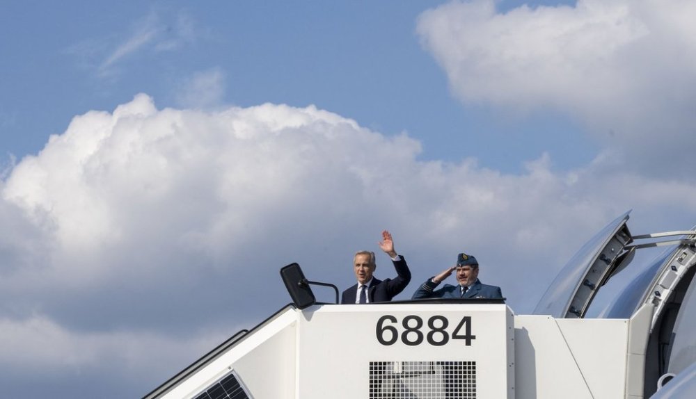 Prime Minister Mark Carney waves as he boards the government plane heading to Riga, Latvia from the airport in Hamburg, Germany on Tuesday, Aug. 26, 2025. THE CANADIAN PRESS/Christinne Muschi