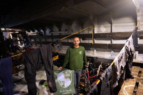 Antoine Polliand, from France, who cycled from Azerbaijan to Portugal with the COP30 Bike Ride, poses with his bicycle in the cargo hold of the Avontuur ship moored in Cascais, outside Lisbon, Saturday, Oct. 4, 2025. He is part of a group heading to Belem, Brazil, the Amazonian city hosting the U.N. COP30 climate talks in November. (AP Photo/Armando Franca)