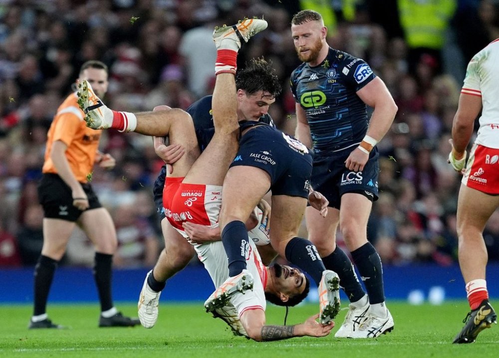 Hull KR's Tyrone May, upside down, is tackled by Wigan Warriors' Brad O'Neill, left, and' Liam Byrne during the Betfred Super League Grand Final rugby match at Old Trafford, in Manchester, England, Saturday, Oct. 11, 2025. (Martin Rickett/PA via AP)