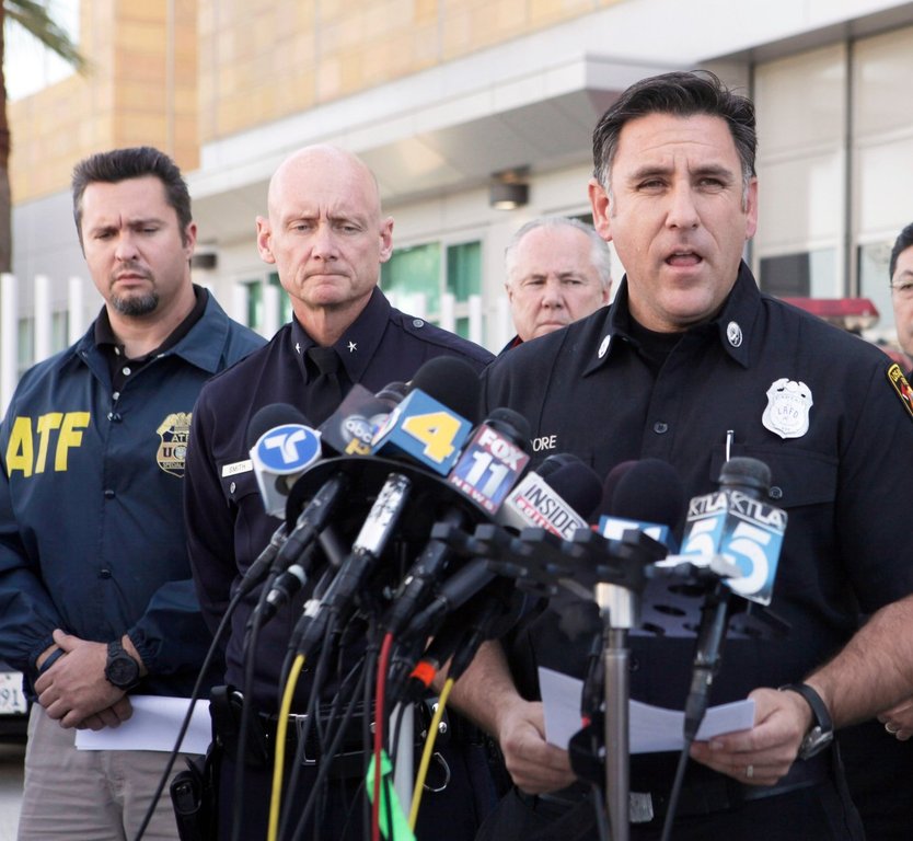 FILE - Los Angeles Fire Department Capt. Jaime Moore, right, addresses the media regarding the arrest of a man in connection with dozens of suspected arson attacks that destroyed parked cars, scorched buildings and rattled much of the nation's second-largest city over the New Year's weekend, Jan. 2, 2012, in Los Angeles. (AP Photo/Nick Ut, File)