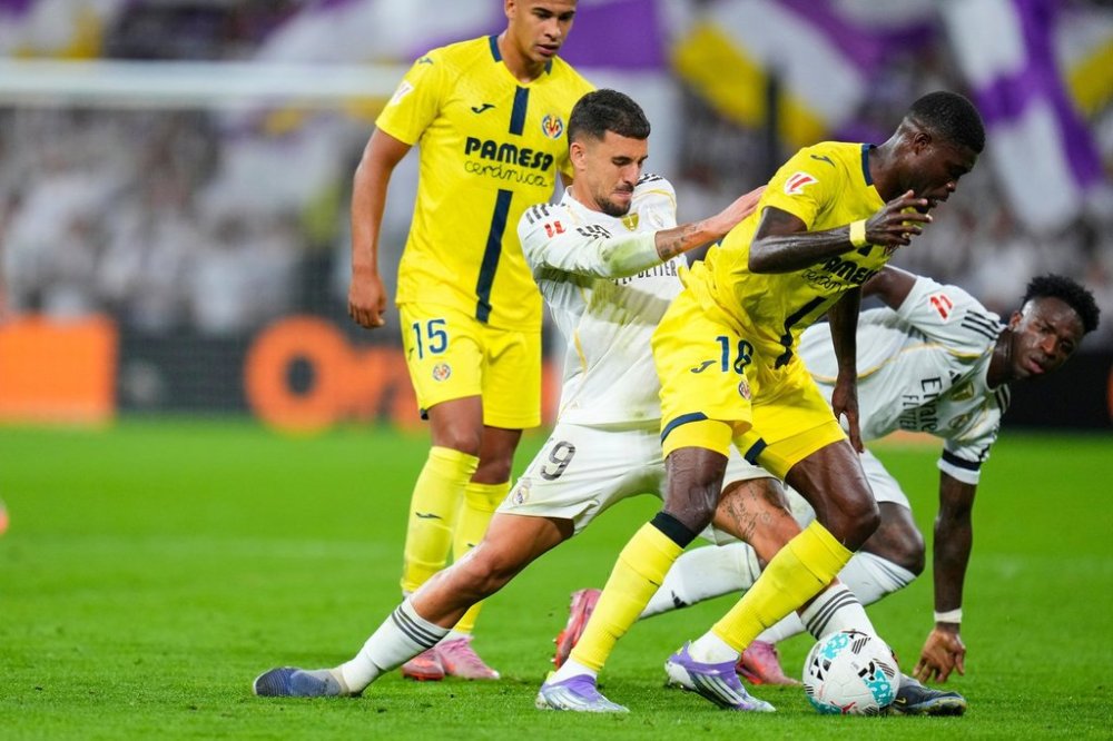 Real Madrid's Vinicius Junior, right, and Dani Ceballos, second from left, challenge for the ball with Villarreal's Santiago Mourino, left, and Pape Gueye during the Spanish La Liga soccer match between Real Madrid and Villarreal at the Santiago Bernabeu stadium in Madrid, Spain, Saturday, Oct. 4, 2025. (AP Photo/Manu Fernandez)