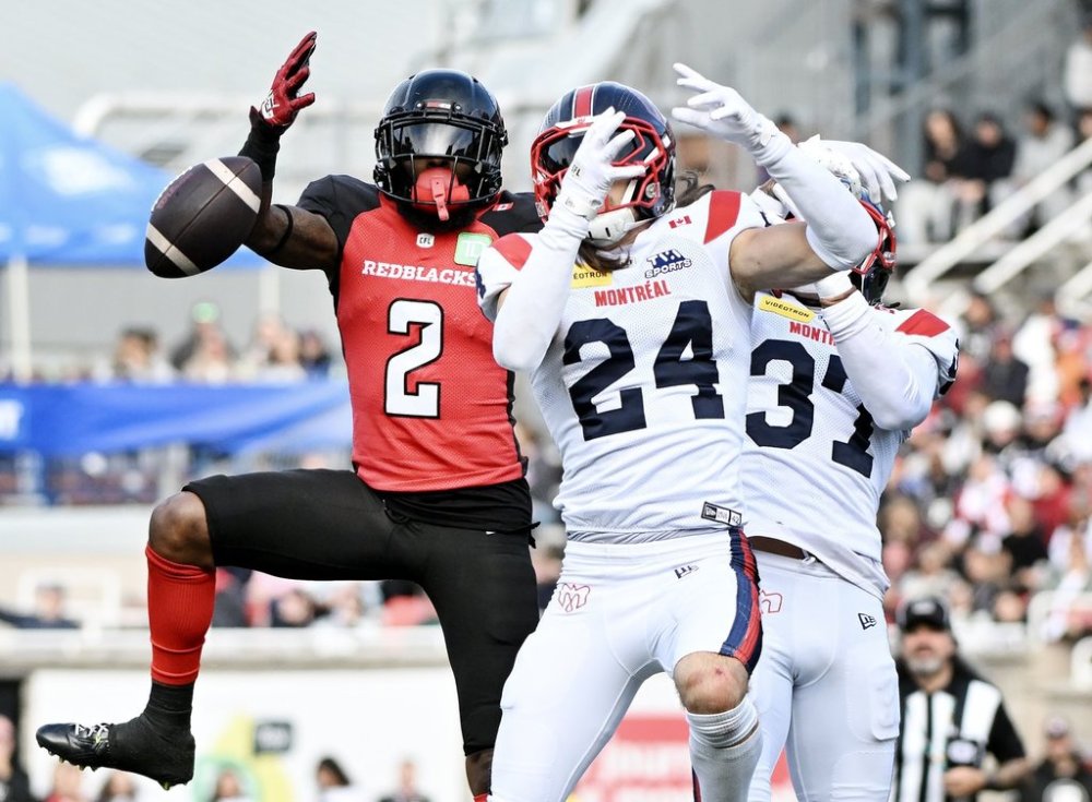 Ottawa Redblacks' Justin Hardy (2) attempts a catch as Montreal Alouettes' Marc-Antoine Dequoy (24) and Wesley Sutton (37) defend during second half CFL football action in Montreal, Monday, Oct. 13, 2025. THE CANADIAN PRESS/Graham Hughes