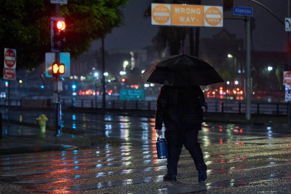 A Federal guard walks to work as gusty showers move over downtown Los Angeles early morning Tuesday, Oct. 14, 2025. (AP Photo/Damian Dovarganes)