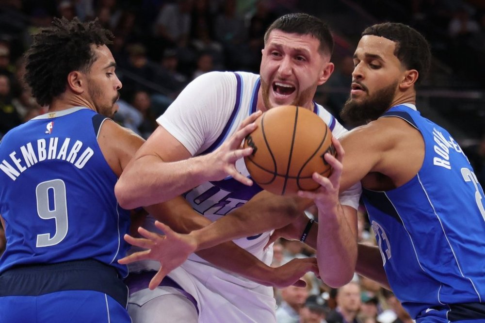 Utah Jazz center Jusuf Nurkić, center, goes to the basket against Dallas Mavericks guard Ryan Nembhard (9) and forward Jeremiah Robinson-Earl, right, during the second half of a preseason NBA basketball game Monday, Oct. 13, 2025, in Salt Lake City. (AP Photo/Rob Gray)