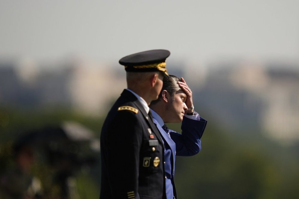 Defense Secretary Pete Hegseth, right, wipes his face while reviewing troops with Army Chief of Staff Gen. Randy George, left, during the POW/MIA National Recognition Day Ceremony at the Pentagon, Friday, Sept. 19, 2025, in Washington. (AP Photo/Julia Demaree Nikhinson)