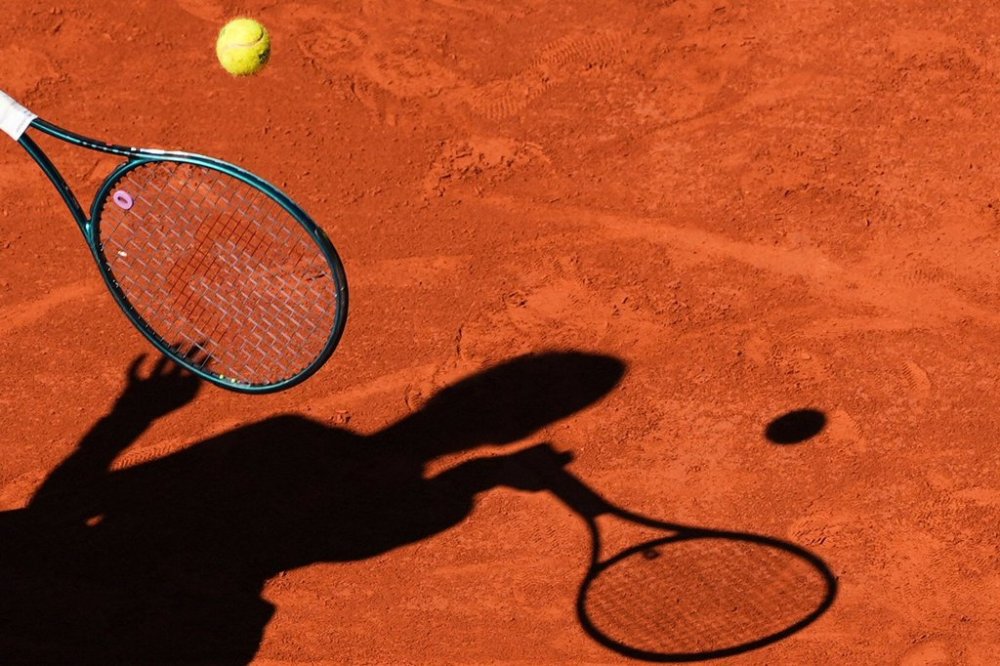 FILE - A player casts a shadow upon the court as they play a shot during the French Tennis Open, Friday, May 30, 2025, at the Roland-Garros stadium in Paris. (AP Photo/Lindsey Wasson, File)