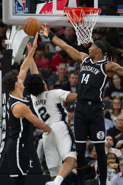 San Antonio Spurs guard Dylan Harper (2) goes to the basket against Brooklyn Nets' Terance Mann (14) and Ben Saraf, left, during the first half of an NBA basketball game, Sunday, Oct. 26, 2025, in San Antonio. (AP Photo/Darren Abate)