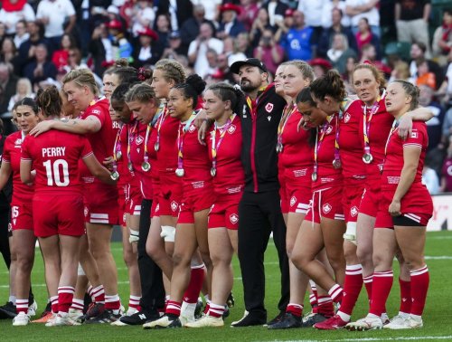 Canada's head coach Head coach Kevin Rouet, centre wearing black, stands with his team as they look on while England celebrates their win in the Women's Rugby World Cup in the London suburb of Twickenham, U.K., Saturday, Sept. 27, 2025. THE CANADIAN PRESS/Sean Kilpatrick