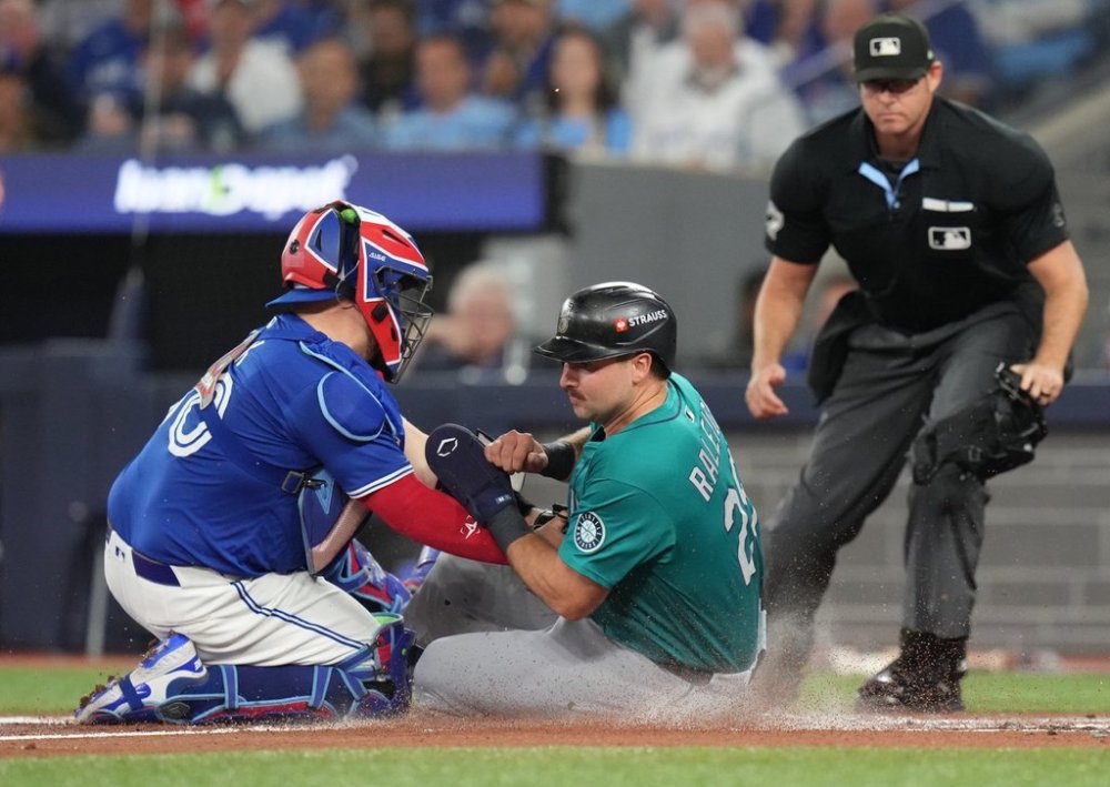 Toronto Blue Jays catcher Alejandro Kirk (30) tags out Seattle Mariners catcher Cal Raleigh (29) at home plate during first inning American League Championship Series baseball action in Toronto on Sunday, Oct. 12, 2025. THE CANADIAN PRESS/Chris Young