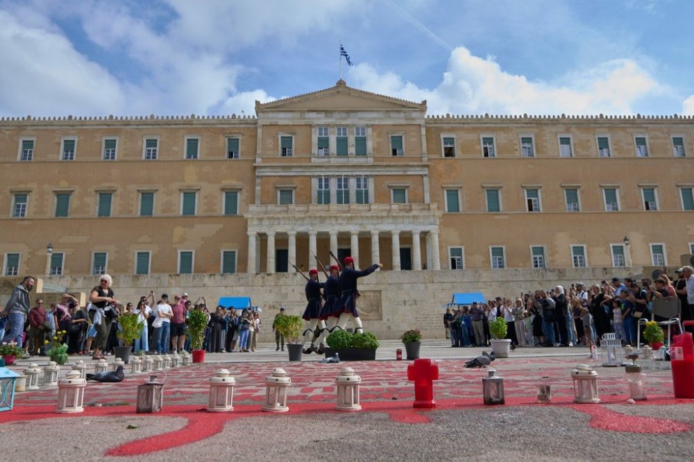 Tourists watch the changing of the guard at the Tomb of the Unknown Soldier in front of the Greek parliament, in Athens, Tuesday, Oct. 21, 2025, as lawmakers debate regulations to protect the monument, recently the focus of protests by relatives of victims of Greece's deadliest train crash. (AP Photo/Petros Giannakouris)