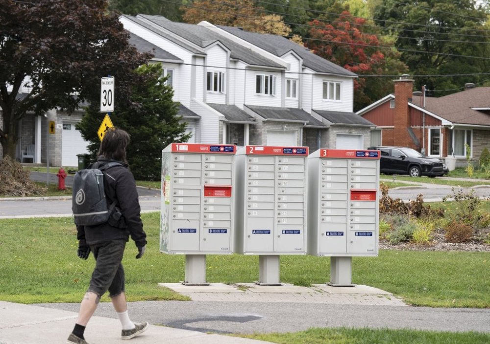 A man walks past community mailboxes in the Pointe-Claire neighbourhood of Montreal on Friday, Sept. 26, 2025. THE CANADIAN PRESS/Christinne Muschi