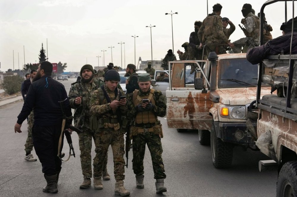 FILE - Syrian fighters check their mobiles, as they patrol a highway in Damascus, Syria, Thursday, Dec. 26, 2024. (AP Photo/Hussein Malla, File)