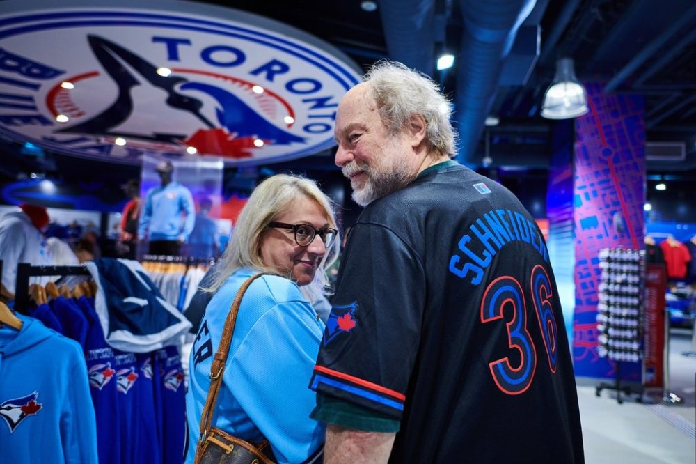Helen Vlahos, left, and Wolf Schneider show their Davis Schneider jerseys as they pose for a portrait while shopping at the Toronto Blue Jays merchandise store outside Rogers Centre in Toronto, on Saturday, Oct. 11, 2025. THE CANADIAN PRESS/Sammy Kogan