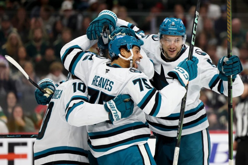 San Jose Sharks right wing Ryan Reaves (75) celebrates with center Ty Dellandrea (10) and defenseman Vincent Desharnais (5) after scoring during the second period of an NHL hockey game against the Minnesota Wild, Sunday, Oct. 26, 2025, in St. Paul, Minn. (AP Photo/Ellen Schmidt)