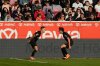 Leverkusen's Alex Grimaldo, left, celebrates with Leverkusen's Jonas Hofmann after scoring his side's third goal during the German Bundesliga soccer match between FSV Mainz 05 and Bayer 04 Leverkusen, in Mainz, Germany, Saturday, Oct. 18, 2025. (AP Photo/Michael Probst)