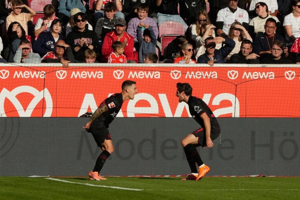 Leverkusen's Alex Grimaldo, left, celebrates with Leverkusen's Jonas Hofmann after scoring his side's third goal during the German Bundesliga soccer match between FSV Mainz 05 and Bayer 04 Leverkusen, in Mainz, Germany, Saturday, Oct. 18, 2025. (AP Photo/Michael Probst)