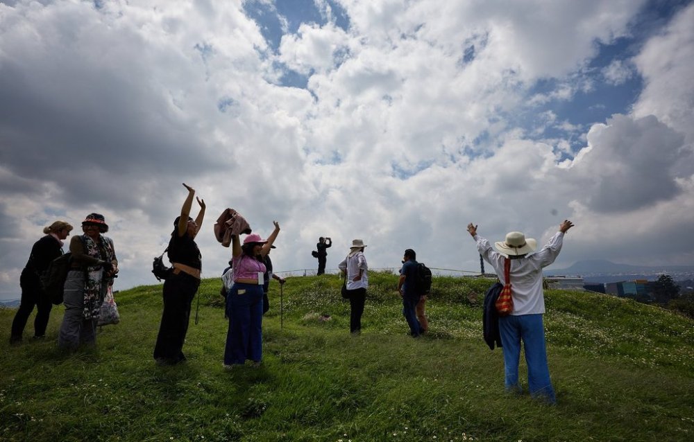 Tourists raise their arms at the Great Basement in the Cuicuilco Archaeological Zone during a tour organized by the National Institute of Anthropology and History in Mexico City, Sunday, Oct. 5, 2025. (AP Photo/Ginnette Riquelme)