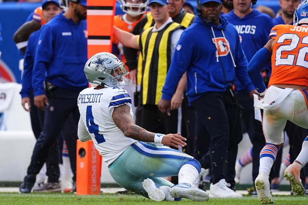 Dallas Cowboys quarterback Dak Prescott (4) slides to a stop for a first down as Denver Broncos safety Brandon Jones (22) defends on the play in the second half of an NFL football game Sunday, Oct. 26, 2025, in Denver. (AP Photo/David Zalubowski)