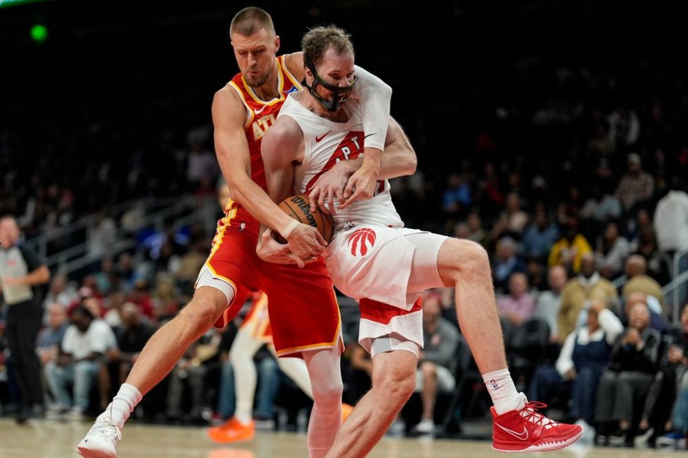 Atlanta Hawks center Kristaps Porzingis (8) and Toronto Raptors center Jakob Poeltl (19) vie for a loose ball during the second half of an NBA basketball game, Wednesday, Oct. 22, 2025, in Atlanta. (AP Photo/Mike Stewart)