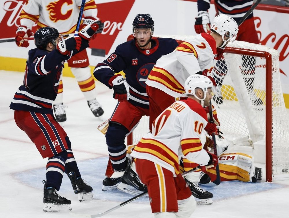 Winnipeg Jets' Jonathan Toews (19) and Nikita Chibrikov (90) celebrate Toews' goal on Calgary Flames goaltender Dustin Wolf (32) during second period NHL action in Winnipeg on Friday, October 24, 2025. THE CANADIAN PRESS/John Woods