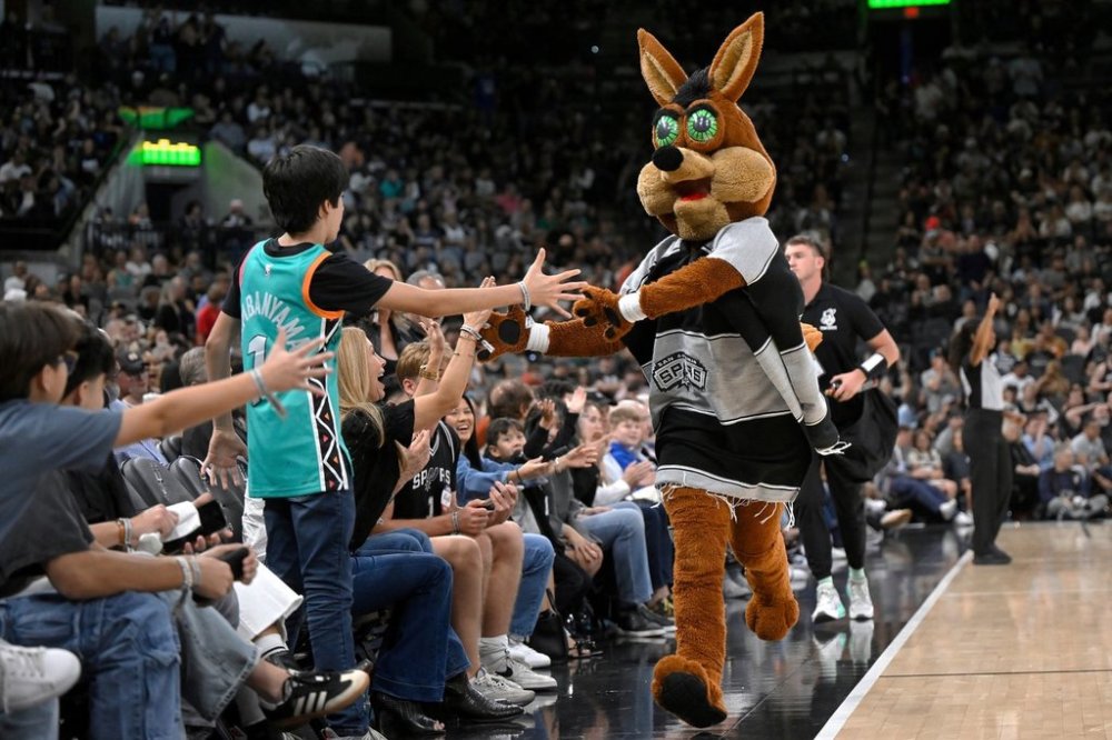 FILE - The Coyote, right, San Antonio Spurs' mascot, greets fans during the second half of an NBA basketball game against the Minnesota Timberwolves, Saturday, Nov. 2, 2024, in San Antonio. San Antonio won 113-103. (AP Photo/Darren Abate, File)