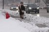 A pedestrian walks on a snow-covered sidewalk in Wheeling, Ill., Monday, Dec. 1, 2025. (AP Photo/Nam Y. Huh)