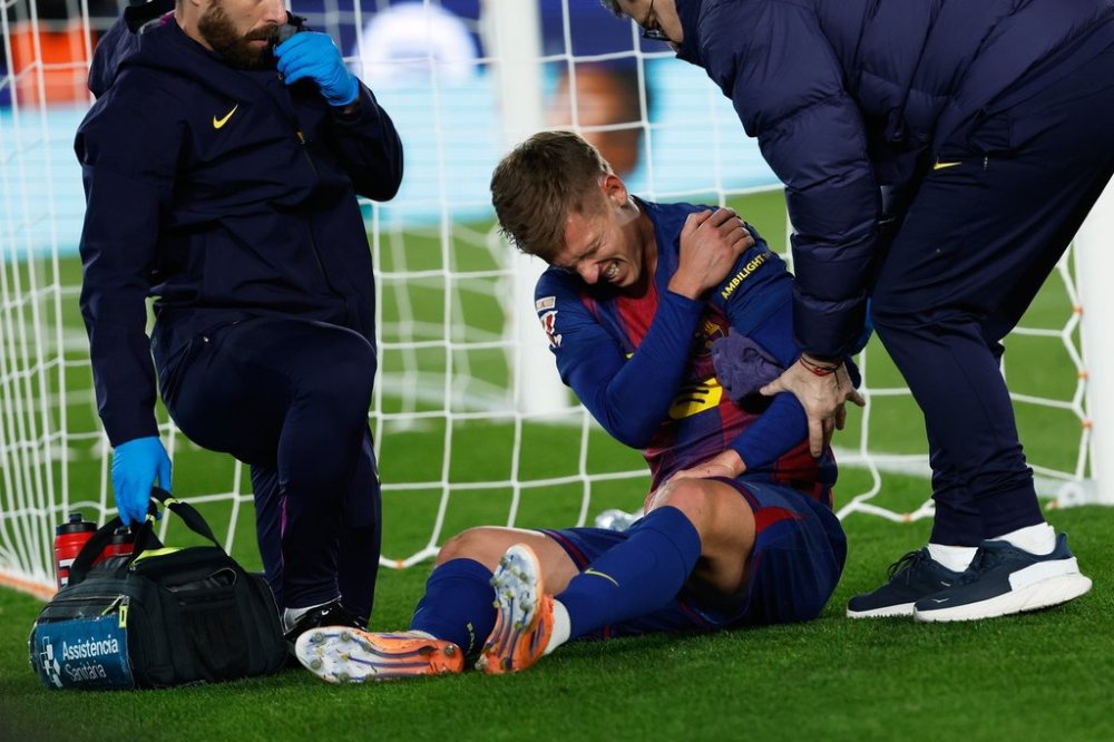 Barcelona's Dani Olmo reacts in pain in his arm after scoring his side's second goal during a Spanish La Liga soccer match between Barcelona and Atletico de Madrid, in Barcelona, Spain, Tuesday, Dec.2, 2025. (AP Photo/Joan Monfort)