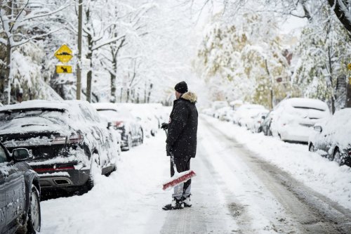 A man cleans snow off his car after heavy snowfall, in Montreal on Tuesday, Nov. 11, 2025. THE CANADIAN PRESS/Christopher Katsarov