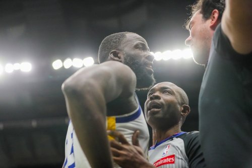 Golden State Warriors forward Draymond Green (23) is held back by referee Courtney Kirkland while talking to New Orleans Pelicans fan Sam Green during the first half of an NBA basketball game against the New Orleans Pelicans in New Orleans, Sunday, Nov. 16, 2025. (David Grunfeld/The Times-Picayune via AP)