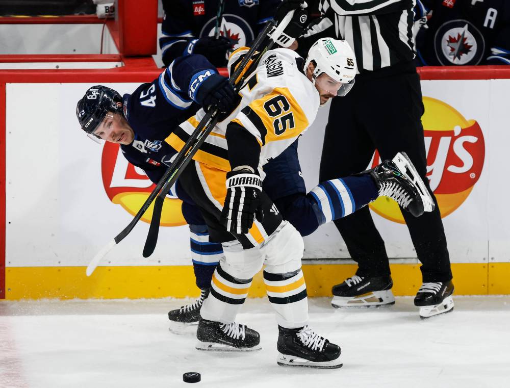Winnipeg Jets' Cole Koepke (45) and Pittsburgh Penguins' Erik Karlsson (65) collide during second period NHL action in Winnipeg, Saturday, Nov. 1, 2025. THE CANADIAN PRESS/John Woods