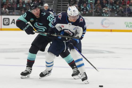 Seattle Kraken defenceman Vince Dunn, left, reaches for the puck against Winnipeg Jets' Kyle Connor, right, during the second period. (Lindsey Wasson / The Associated Press)