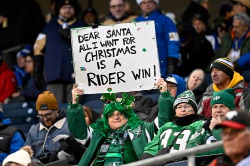 A Saskatchewan Roughriders fan holds a poster board sign prior to first half CFL football action between the Montreal Alouettes and Saskatchewan Roughriders at the 112th Grey Cup, in Winnipeg on Sunday, Nov. 16, 2025. (Fred Greenslade / The Canadian Press)