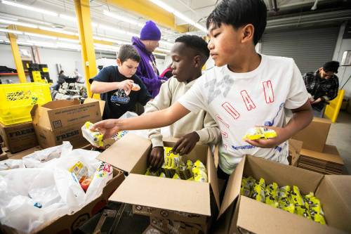 MIKAELA MACKENZIE / FREE PRESS
                                Grade five students Jordan Musseau (left), Elisha Tardeen, and Charles Malonzo pack meals at Harvest Manitoba’s Meals2Go program kickoff on Monday.