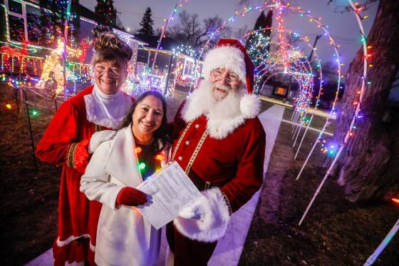 Brad and Roxanne Wallace, dressed as Santa and Mrs. Claus, with city councillor Devi Sharma, who assisted them in getting a permit for their Christmas light display. (John Woods / Free Press)