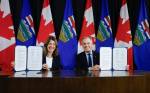 Prime Minister Mark Carney, right, signs an MOU with Alberta Premier Danielle Smith in Calgary, on Nov. 27. (Jeff McIntosh / The Canadian Press)